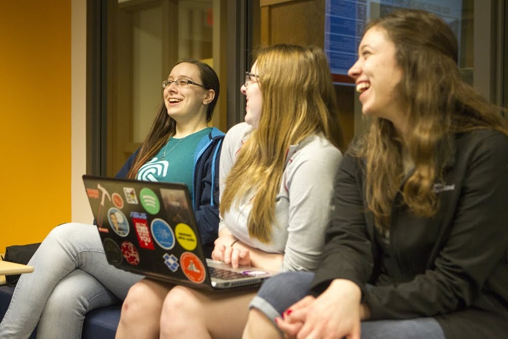 Photo of three women students at a club meeting