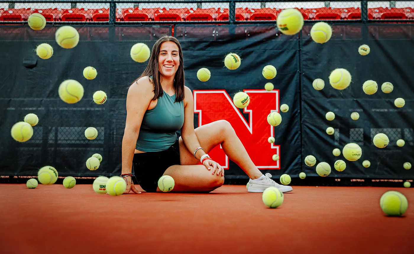 Tennis balls bounce around Isabel Adrover Gallego as she sits for a photo on the tennis court.