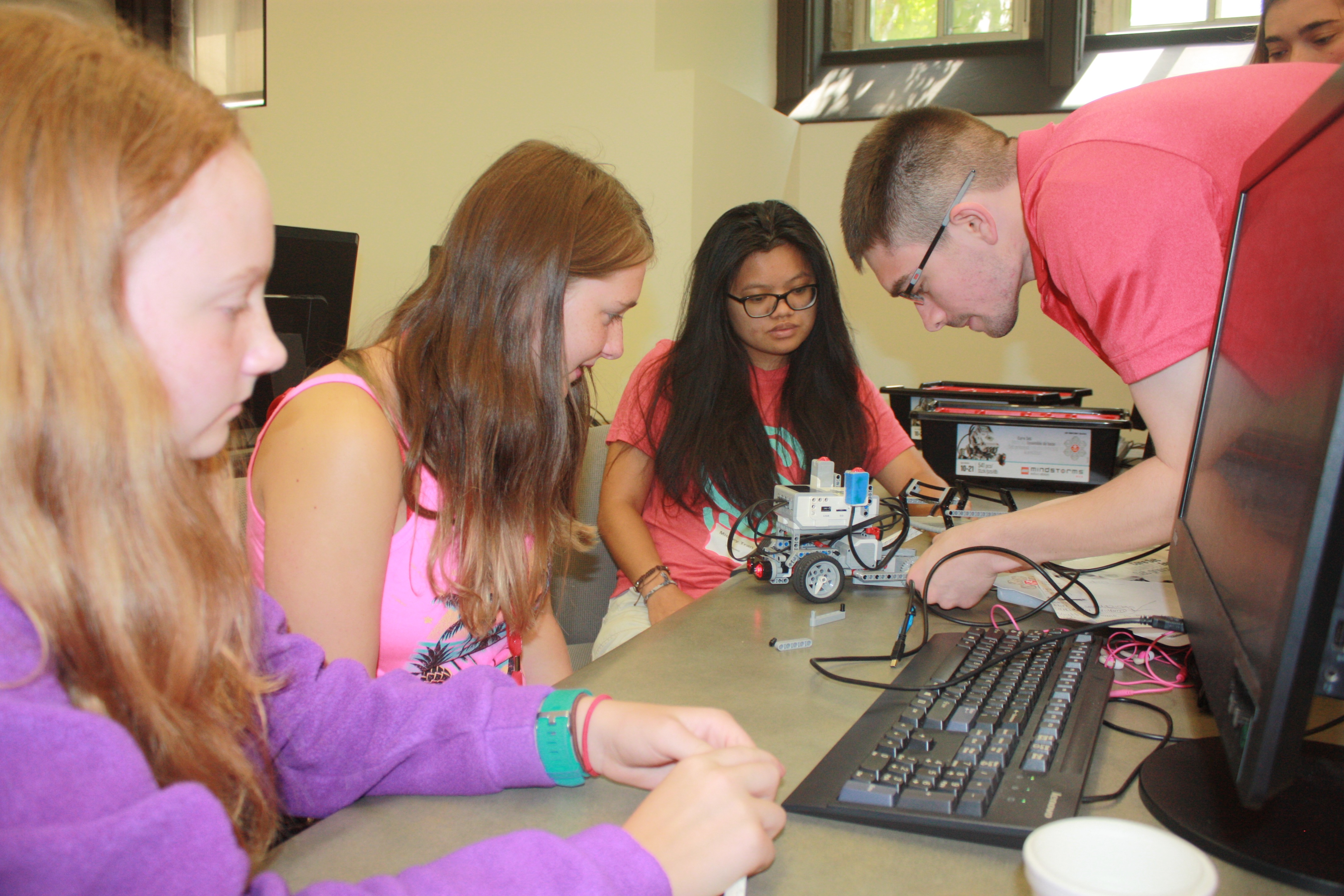 Student mentors Mickey Tran and Tyler Barker help two Girl Scouts program a robot at this month's annual summer computing camp.