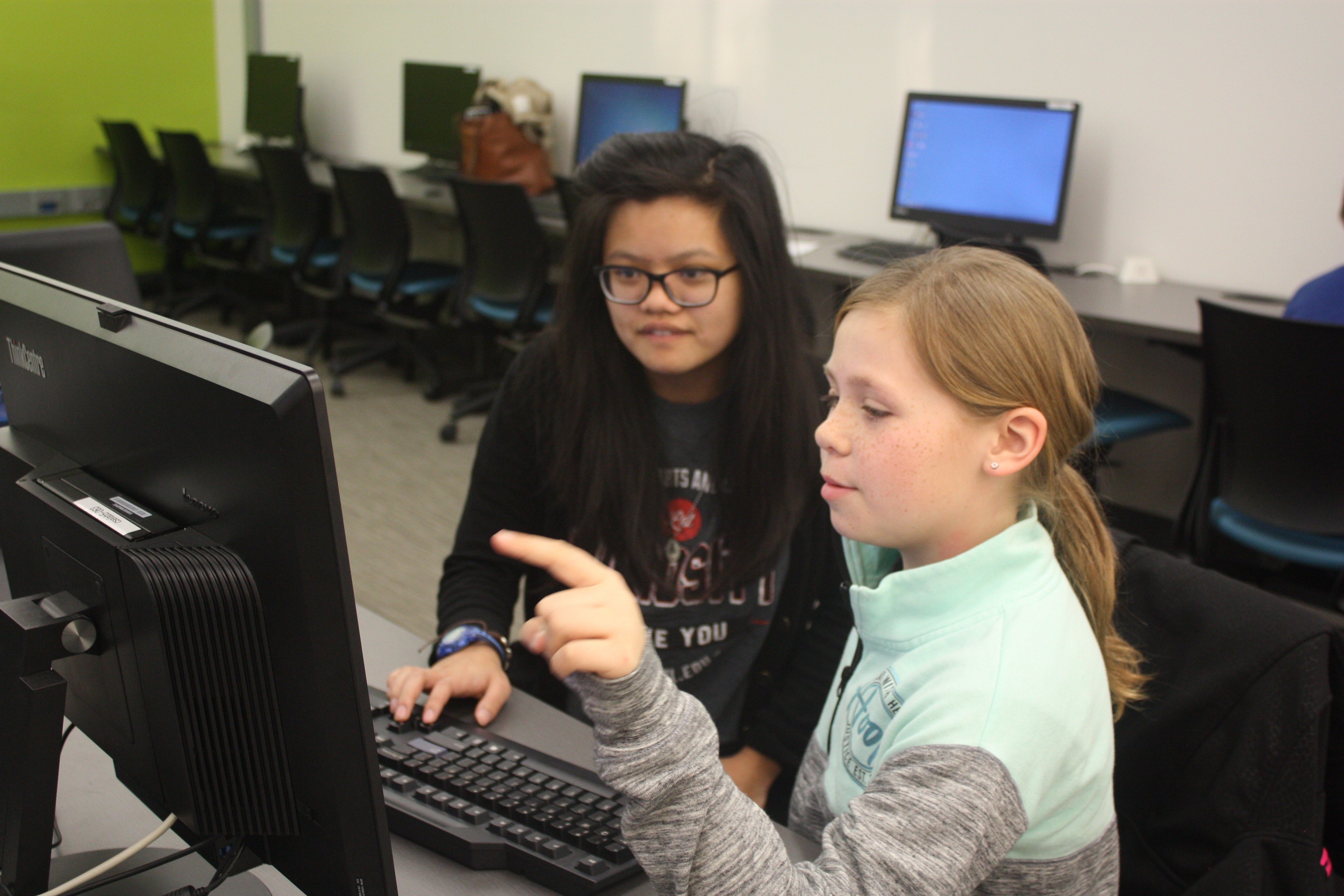 Mentor Mickey Tran helps a student with her coding project during the first CADDY workshop.