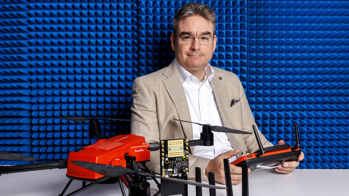 Mehmet Can Vuran, Dale M. Jensen Chair and Professor of computing at the University of Nebraska–Lincoln, poses with mobile and stationary elements for 6G wireless connectivity in a room with blue padded walls.