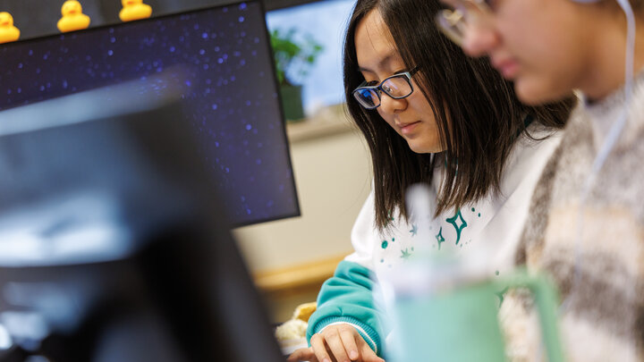 Two students type and work at a computer