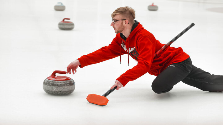 Brett Johnson slides a curling stone Jan. 20 during the club team's bonspiel at the Breslow Ice Hockey Center.