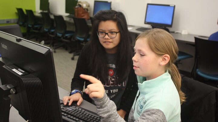 Mentor Mickey Tran helps a student with her coding project during the first CADDY workshop.