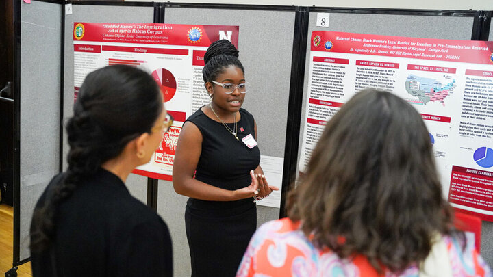 A student presents research during a poster session.
